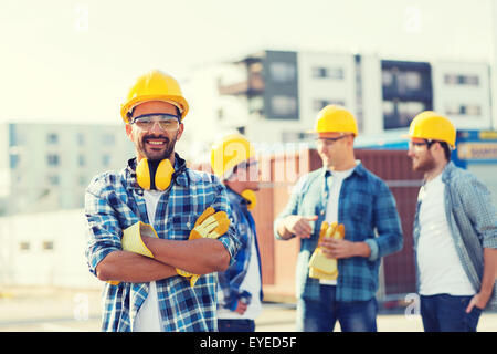 Gruppo di costruttori sorridente in hardhats all'aperto Foto Stock