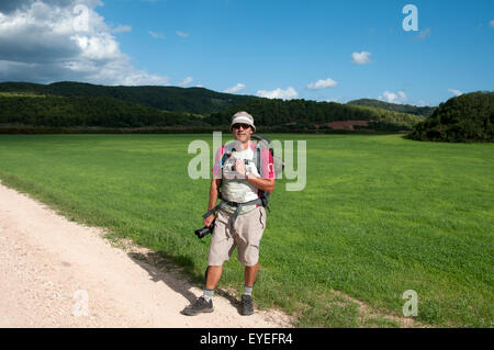Un viandante si erge di fronte a un campo verde vicino a Spiaggia Algaiarens sul Cami de Cavalls bridal path menorca Spagna Foto Stock