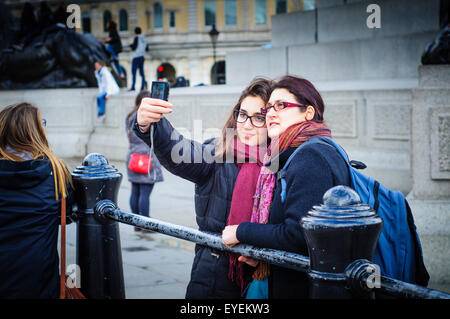 Mamma e figlia tenendo selfie con telefono cellulare, Trafalgar Square, London, Regno Unito Foto Stock