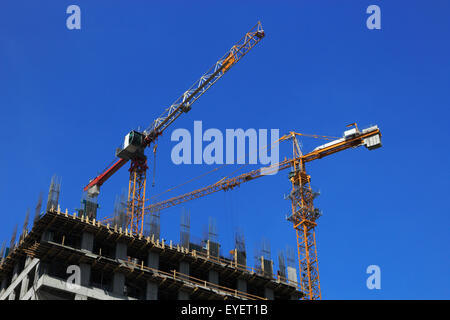 Due gru sul sito di costruzione del nuovo edificio per uffici. Foto Stock