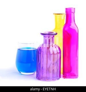 Tre bottiglie colorate e un vetro, isolati su sfondo bianco Foto Stock