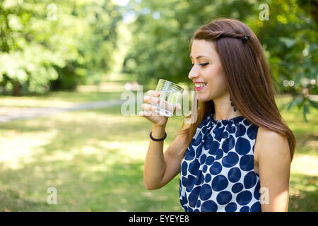 Giovane donna di bere un bicchiere di acqua all'aperto Foto Stock