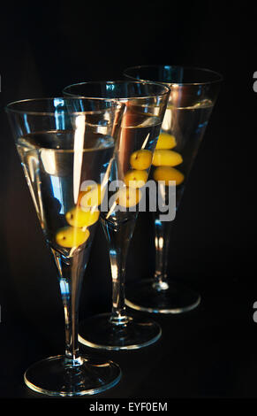 Tre cocktail Martini con le olive contro uno sfondo scuro Foto Stock