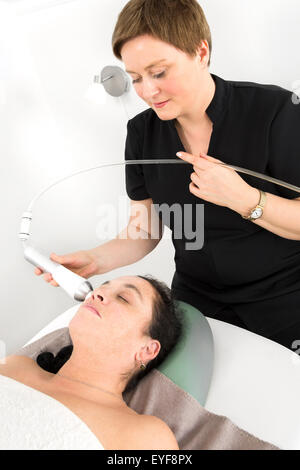 Donna client riceve viso trattamento snellente alla clinica di bellezza Foto Stock