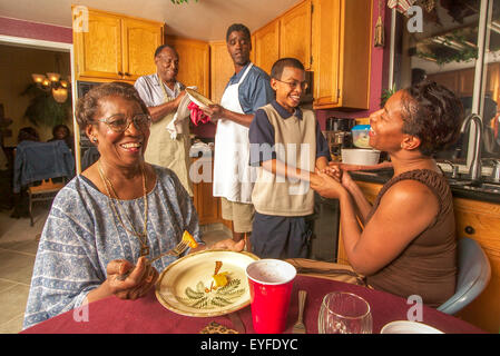 Tre generazioni di una famiglia americana africana interagire con affetto nel loro Corona, CA, cucina. Nota Gli uomini piatti di essiccazione. Foto Stock