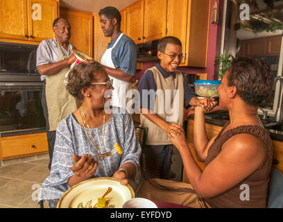 Tre generazioni di una famiglia americana africana interagire con affetto nel loro Corona, CA, cucina. Nota Gli uomini piatti di essiccazione. Foto Stock