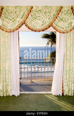 Il vento soffia tende a un hotel sul mare in Laguna Beach, CA, l'inquadratura di un balcone che si affaccia sull'Oceano Pacifico surf al tramonto. Nota lunghe ombre. Foto Stock