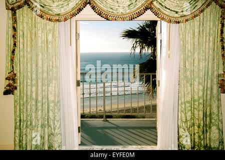 Il vento soffia tende a un hotel sul mare in Laguna Beach, CA, l'inquadratura di un balcone che si affaccia sull'Oceano Pacifico surf al tramonto. Nota lunghe ombre. Foto Stock