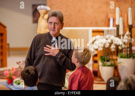 All'incoronazione di Maria in una Laguna Niguel, CA, chiesa cattolica, monsignor risposte le domande dei bambini sulla cerimonia. Può devozione alla Beata Vergine Maria sono una Cattolica Romana tradizionale rituale venerandola come "la regina di maggio." Nota statua in background. Foto Stock