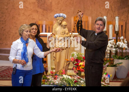 All'incoronazione di Maria in una Laguna Niguel, CA, chiesa cattolica, monsignor e ai suoi volontari visualizzare un Rosario gigante mentre rispondere le domande dei bambini sulla cerimonia. Può devozione alla Beata Vergine Maria sono una Cattolica Romana tradizionale rituale venerandola come "la regina di maggio." Nota statua in background. Foto Stock