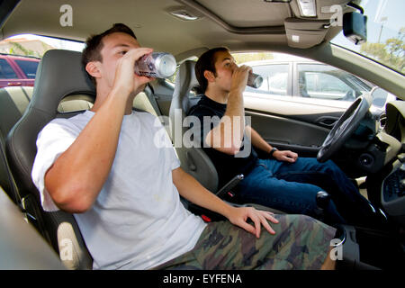 Due giovani uomini adulti bere birra in una macchina parcheggiata in un Southern California parcheggio. La chiave di accensione è stata rimossa, assicurando che la vettura non può essere guidato. Foto Stock