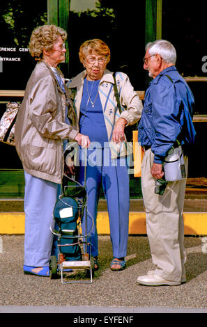 Tre persone anziane con malattia polmonare ostruttiva cronica (COPD) trasportare portatili concentratori di ossigeno (POC) che convertono l'aria circostante in ossigeno concentrato. Foto Stock