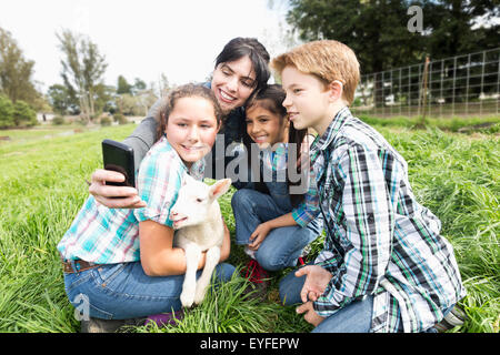 Donna con ragazze(6-7, 12-13) e ragazzo (10-11) di fotografare con agnello Foto Stock