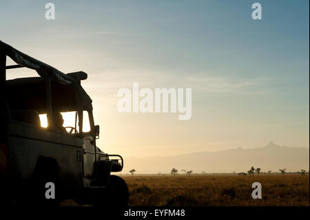 Silhouette di driver in 4x4 di fronte al monte Kenya all'alba, Ol Pejeta Conservancy; Kenya Foto Stock