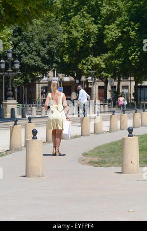 Uomo in bicicletta guardando sopra la spalla alla giovane donna che indossa abiti piuttosto il trasporto delle borse della spesa a Bordeaux, Francia Foto Stock