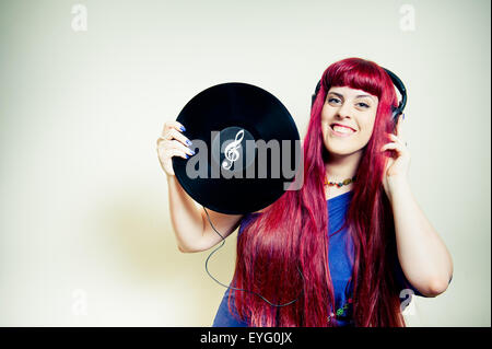 Giovane donna graziosa ballando con le cuffie e dischi in vinile con chiave di violino simbolo Foto Stock