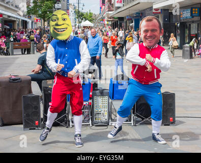 Buskers indossando maschere di persone famose/celebrites eseguendo su Northumberland San a Newcastle upon Tyne. In Inghilterra. Regno Unito Foto Stock