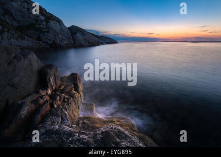 Forme d'onda colpendo la riva durante il tramonto a la westcoast della Norvegia Foto Stock