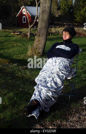 Lessebo, Svezia, donna appoggiato avvolto in una coperta nel giardino di Foto Stock