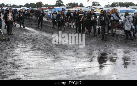 Wacken, Germania. 29 Luglio, 2015. I visitatori del W.O.A. (Wacken Open Air) a piedi attraverso il fango sul sito del festival in Wacken, Germania, 29 luglio 2015. Heavy Metal tifosi provenienti da tutto il mondo vengono a Wacken per celebrare il più grande del mondo di heavy metal festival. Credito: dpa picture alliance/Alamy Live News Foto Stock