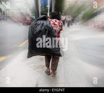 Senior tira un sacchetto di plastica sulla schiena per le strade di Shenzhen Foto Stock