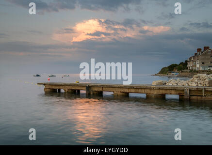 Nuvole temporalesche formante al tramonto sulla baia tranquilla con jetty Foto Stock