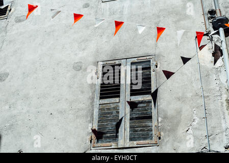 Il bianco e il rosso bandiere decorare la parete della vecchia casa abbandonata in Saint Jean de Maurienne, Francia Foto Stock