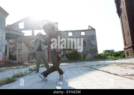 Giovane maschio americano africano hip hop o street dancer con ricci capelli afro eseguendo la sua energica dance routine in una città squar Foto Stock