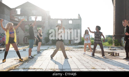 Energici giovani hip hop ballerini di strada di svolgere la loro routine in una piazza urbana retroilluminati da un sole luminoso flare su hig Foto Stock