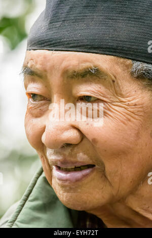 Ritratto di un felice vecchio uomo nepalese mongoloid carattere con il cappuccio sulla testa e i capelli grigi e la faccia rugosa Foto Stock