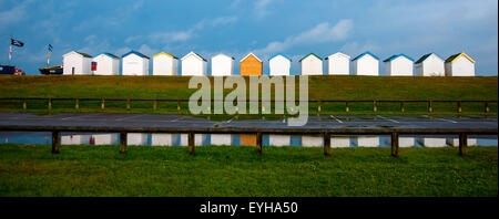 Cabine sulla spiaggia, a Lancing West Sussex sotto un cielo tempestoso riflessa nell'acqua Foto Stock