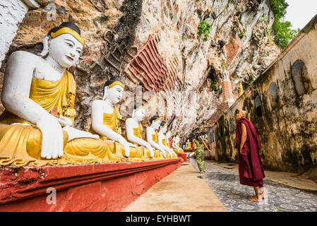 Monaco guardando il sedere statue di Buddha, Kawgun grotta, di Hpa-an, Karen o Stato di Kayin, Myanmar Foto Stock