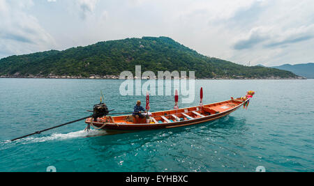 Uomo tailandese la sterzatura di un longtail boat, isola di Koh Tao, Golfo di Thailandia, Tailandia Foto Stock