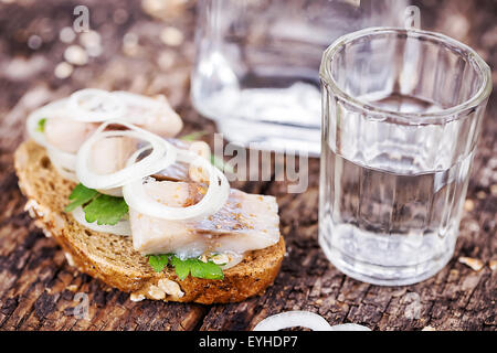 Pane nero con le aringhe e vodka sul tavolo di legno Foto Stock