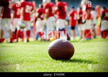 Close up di un american football in campo, i giocatori in background Foto Stock