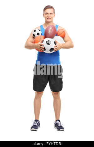 A piena lunghezza Ritratto di una giovane atleta tenendo un mazzetto di differenti tipi di palle sportive isolati su sfondo bianco Foto Stock