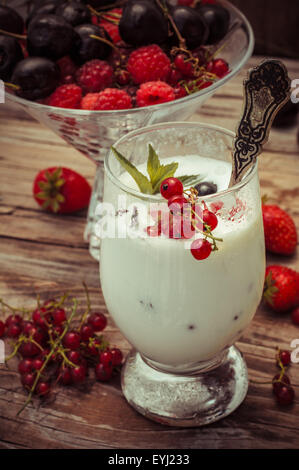 Dessert di gelato per vetro e frutti di bosco freschi, ciliegie,le uve secche di Corinto,Fragole.Foto oscurata. Foto Stock