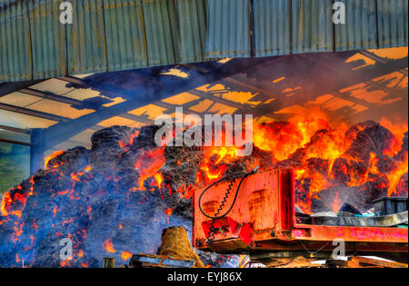 Plumpton, Lewes, East Sussex, Regno Unito. 30th luglio 2015. Calore intenso creato dalle balle di fieno bruciate nel fienile. I vigili del fuoco contengono la scena e utilizzano edifici adiacenti e serbatoio carburante. Dovrebbero essere sulla scena per alcuni giorni Foto Stock