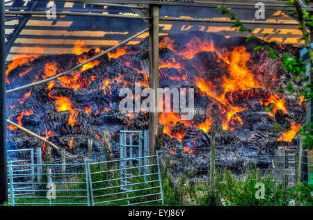 Plumpton, Lewes, East Sussex, Regno Unito. 30th luglio 2015. Calore intenso creato dalle balle di fieno bruciate nel fienile. I vigili del fuoco contengono la scena e utilizzano edifici adiacenti e serbatoio carburante. Dovrebbero essere sulla scena per alcuni giorni Foto Stock