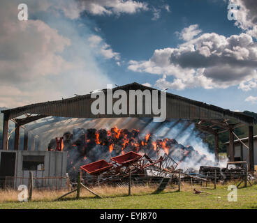 Plumpton, Lewes, East Sussex, Regno Unito. 30th luglio 2015. Calore intenso creato dalle balle di fieno bruciate nel fienile. I vigili del fuoco contengono la scena e utilizzano edifici adiacenti e serbatoio carburante. Dovrebbero essere sulla scena per alcuni giorni Foto Stock