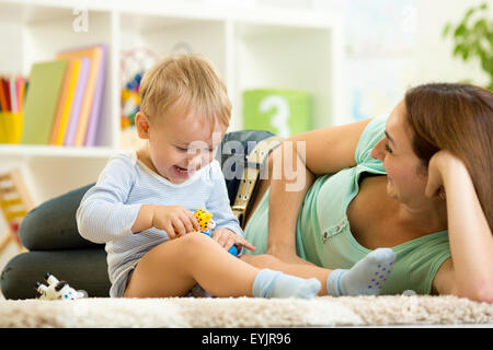 Bambino felice tiene giocattolo animale giocando con mom in vivaio Foto Stock