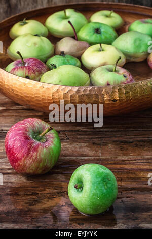 Raccolto autunnale di mele nel recipiente di acqua su sfondo di legno.Foto oscurata. Foto Stock