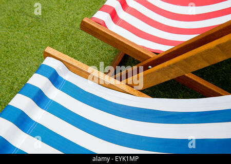 Blu/Rosso e bianco striato di sedie a sdraio, sul prato con nessuno sat. Foto Stock