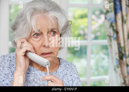 Preoccupato Senior donna rispondendo Telefono in casa Foto Stock