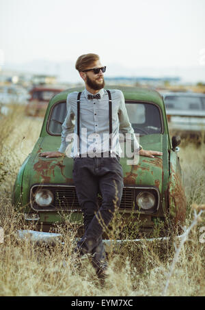 Ritratto di un giovane bello elegante uomo, indossa una camicia e bow tie-in con la vecchia auto Foto Stock