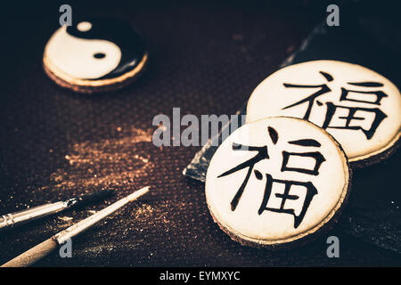 Dipinte a mano e i cookie con i caratteri cinesi 'fortuna', bambù e Yin Yang. Messa a fuoco selettiva. Foto Stock