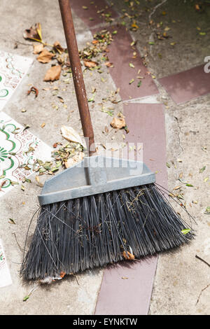 Scopa spazza caduta foglie dal calcestruzzo marciapiede Foto Stock