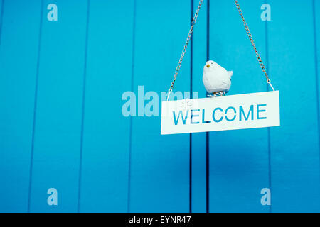 In legno rustico segno di benvenuto appeso su sfondo blu Foto Stock