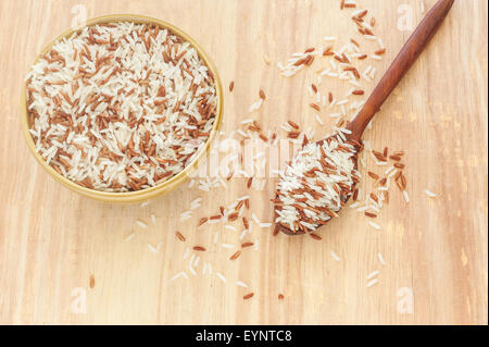 Riso berry, riso marrone in cucchiaio di legno e ciotola su legno Foto Stock