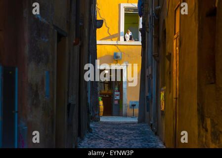 Roma quartiere ebraico, uno chef osserva passanti nella strada sotto la sua finestra della cucina in Sant Angelo quartiere ebraico di Roma, Italia. Foto Stock